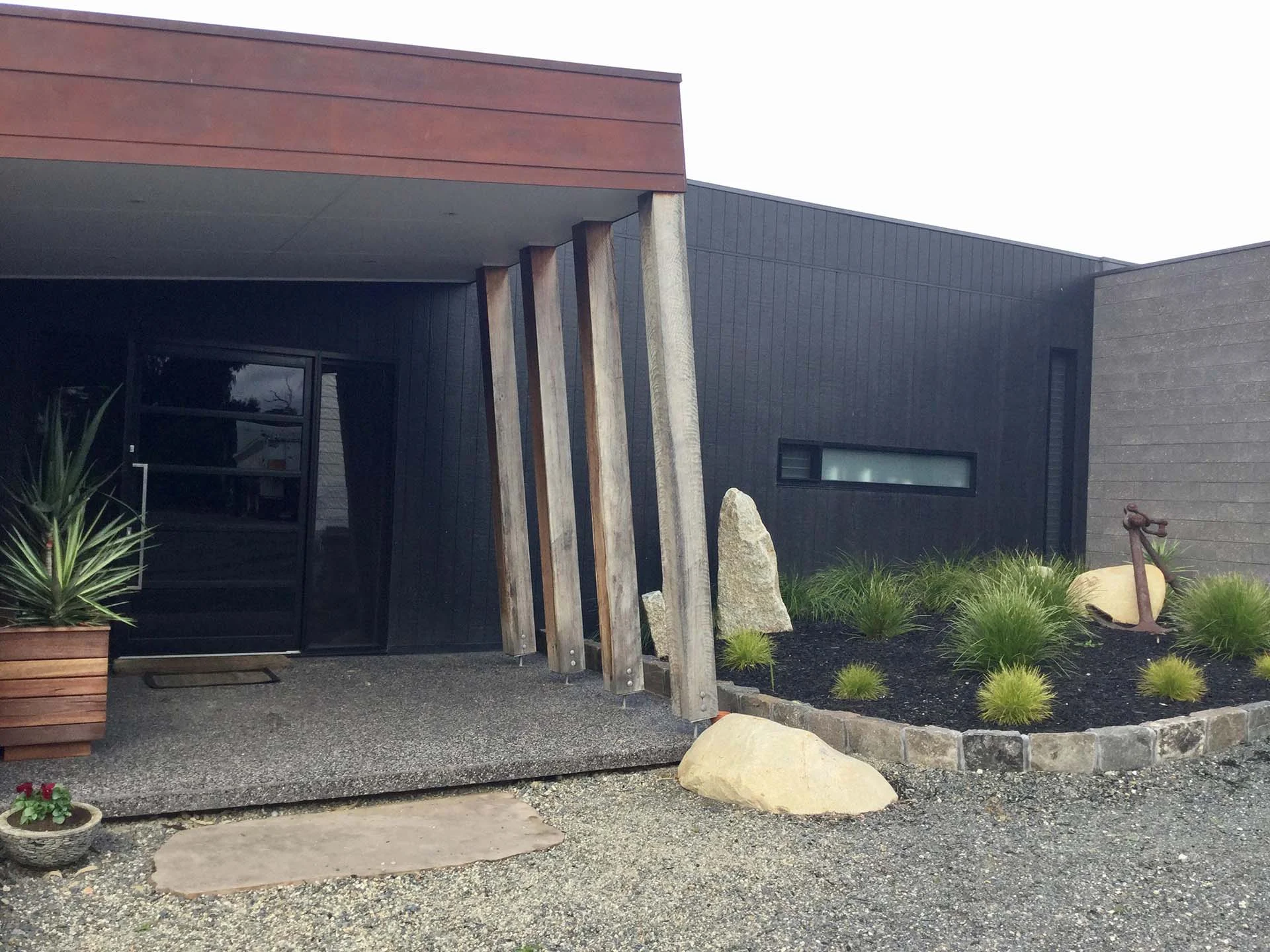 Charcoal cladding and timber posts at a contemporary home entry
