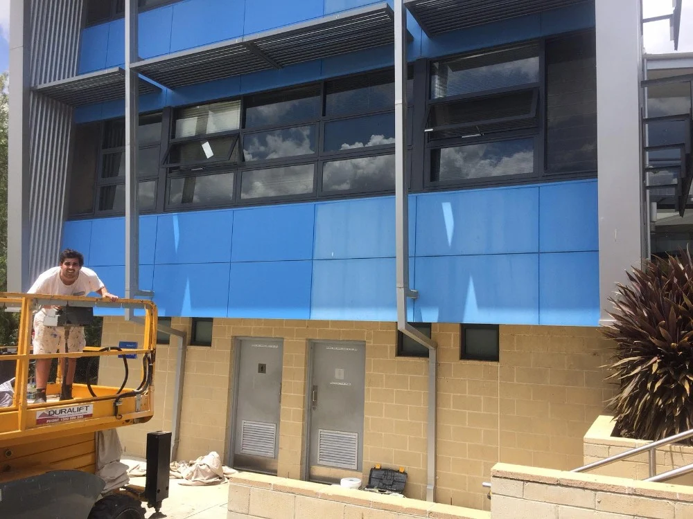 Painter on an elevated work platform painting a commercial facade